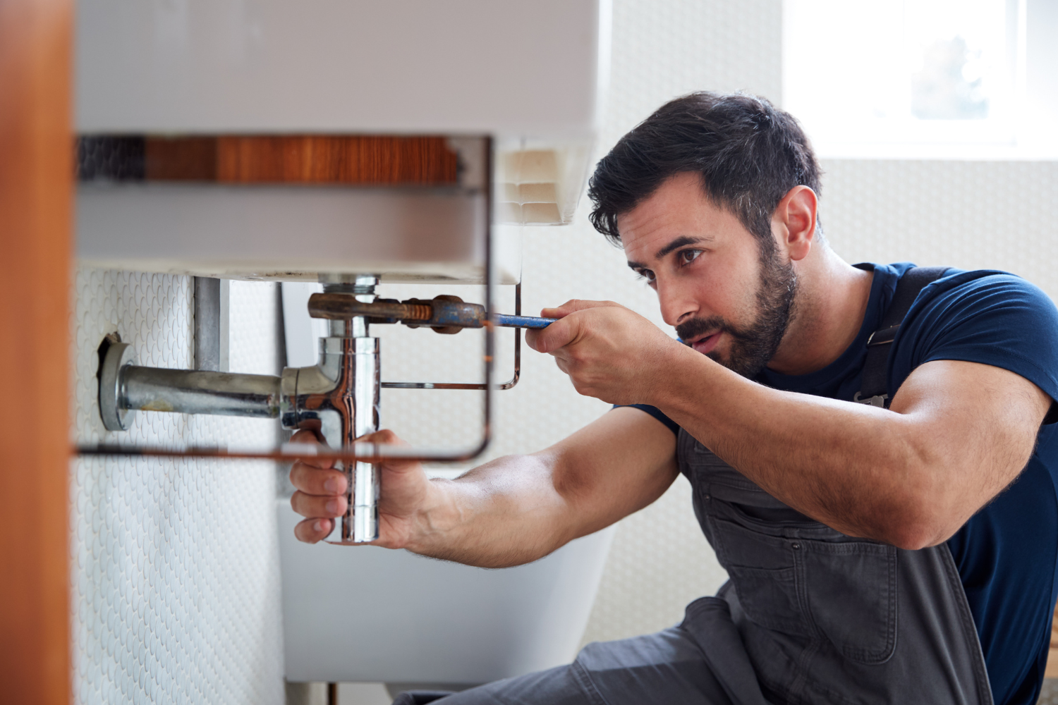 Plumber fixing pipework under a sink